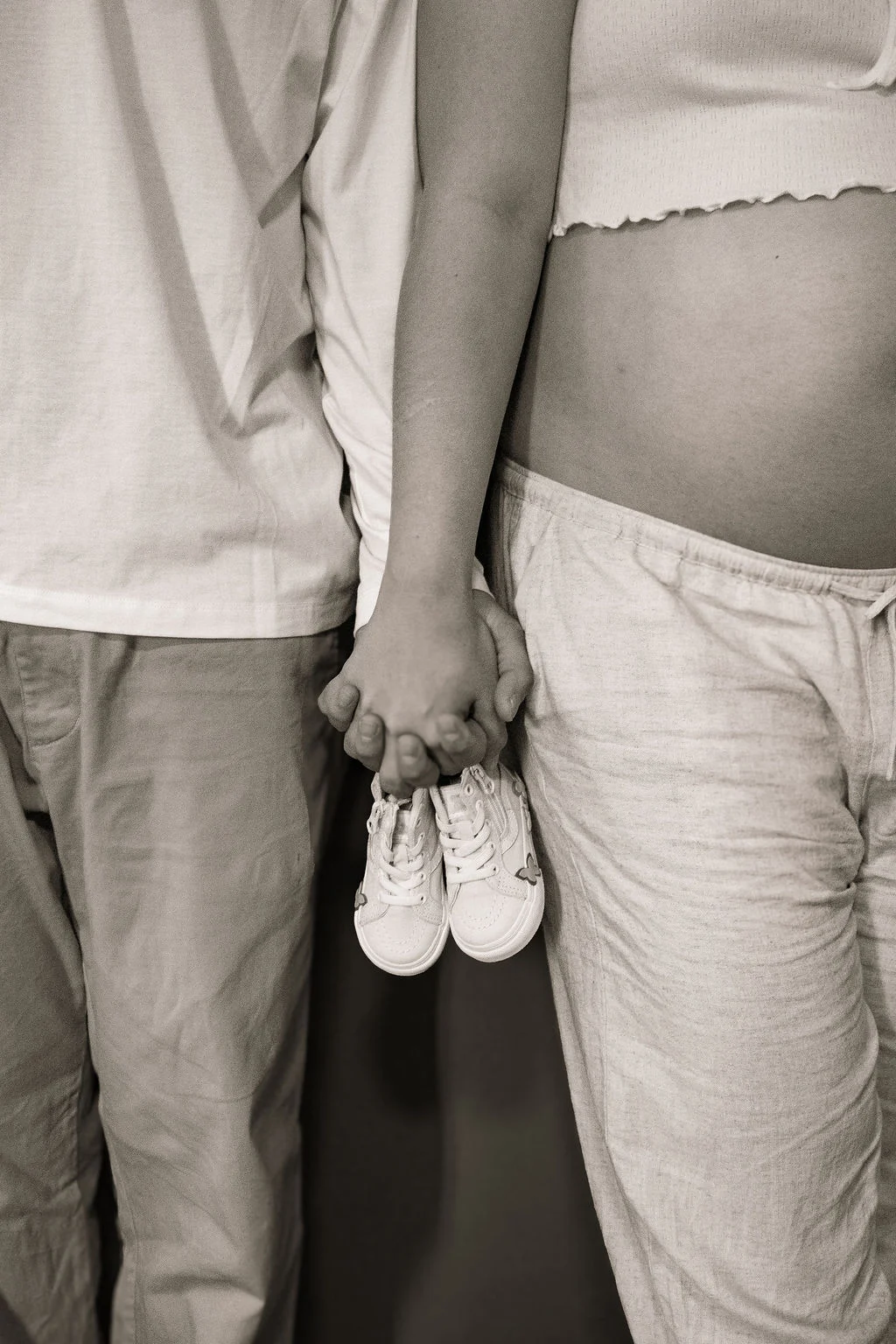 Pareja tomada de la mano con pequeños zapatos de bebé