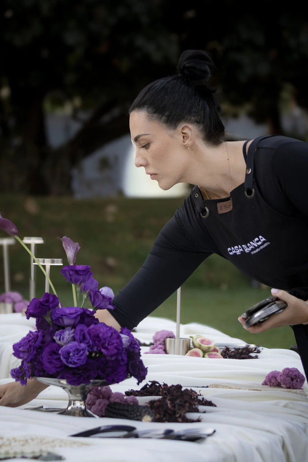 Preparativos de una mesa con flores moradas para un evento