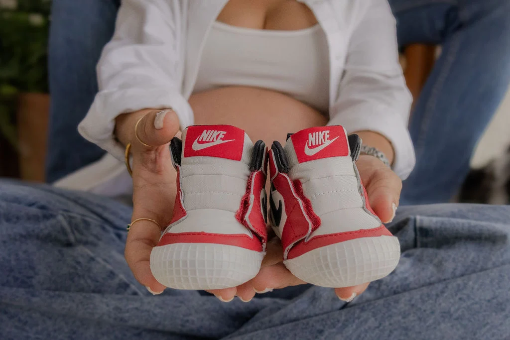 Detalle de tenis de bebé sobre las manos de sus papás