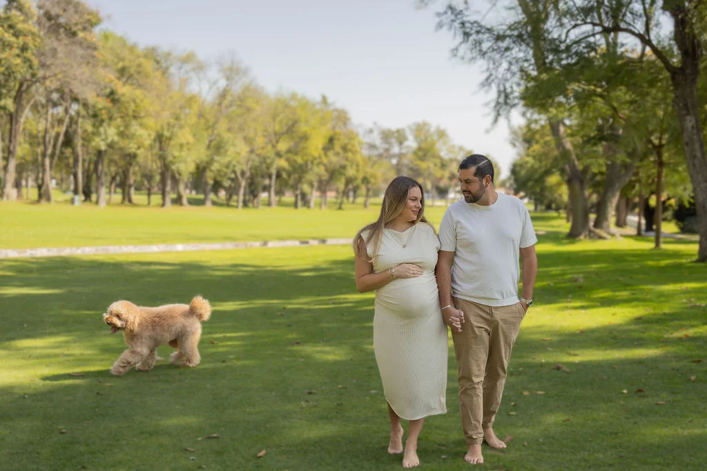 Futuros papás caminando juntos en un jardín con su perro